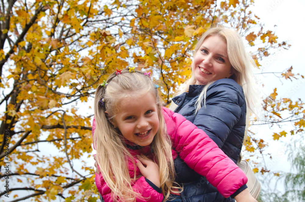 A little girl walks and plays with her mother in the park. Autumn landscape with golden leaves A little girl walks and plays with her mother in the park. Autumn landscape with golden leaves
