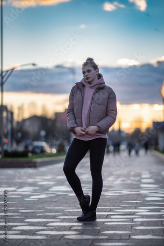 Portrait of a young beautiful blonde girl in the evening on a city street.