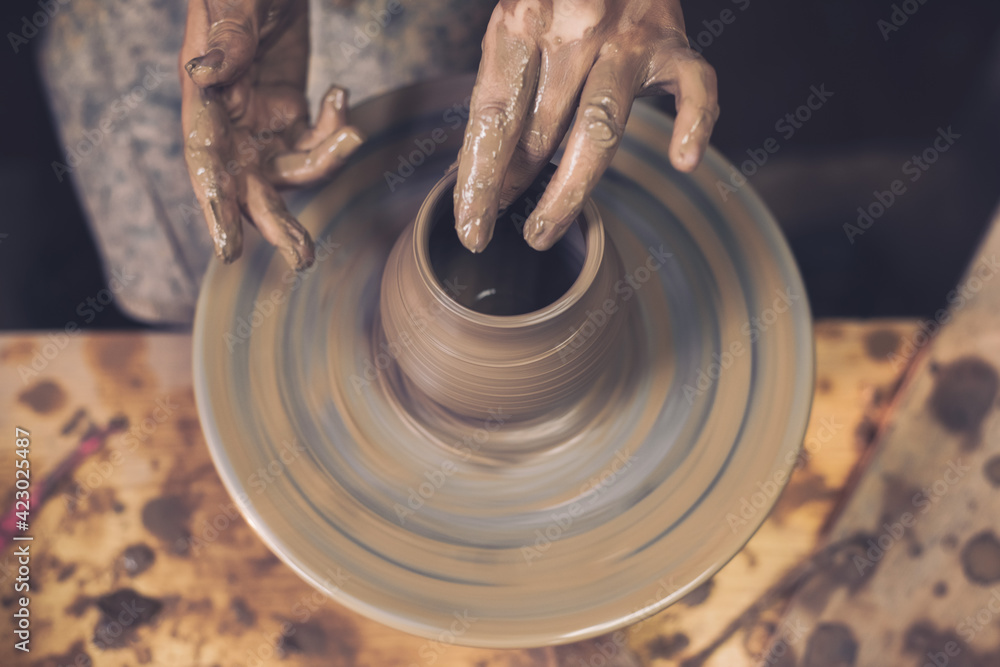 In the ceramics workshop. Beautiful hands of the master make peas on a potting wheel. Place for your text.