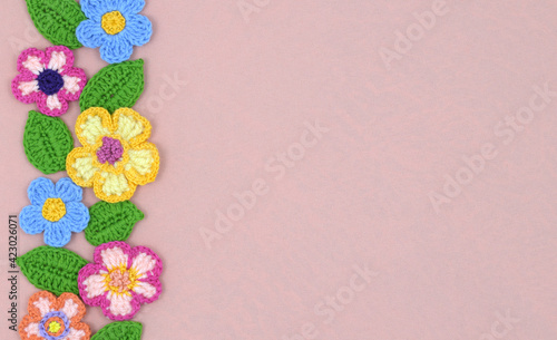 Handcrafted background with flowers and leaves in a row on pink textile for a spring mood card. 