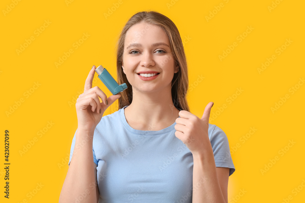 Young woman with inhaler showing thumb-up on color background Young woman with inhaler showing thumb-up on color background