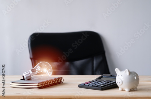 Wallpaper Mural calculato,Piggy bank,book and light bulb on wooden table work place at home. Idea for saving money concept. Torontodigital.ca