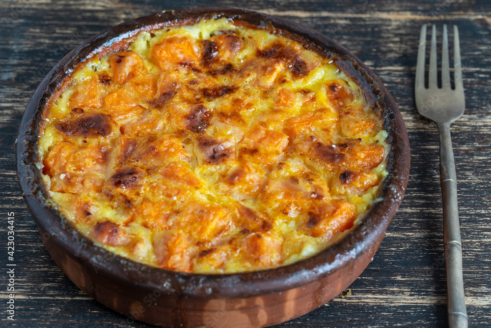 Baked yellow pumpkin in milk sauce with honey and egg on a plate on the wooden table, top view. Vegetarian food Baked yellow pumpkin in milk sauce with honey and egg on a plate on the wooden table, top view. Vegetarian food