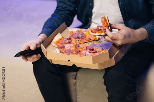 Unrecognizable hand opening delivery box with hot delicious pizza inside. Food delivery service at party catering concept. Opening a pizza box