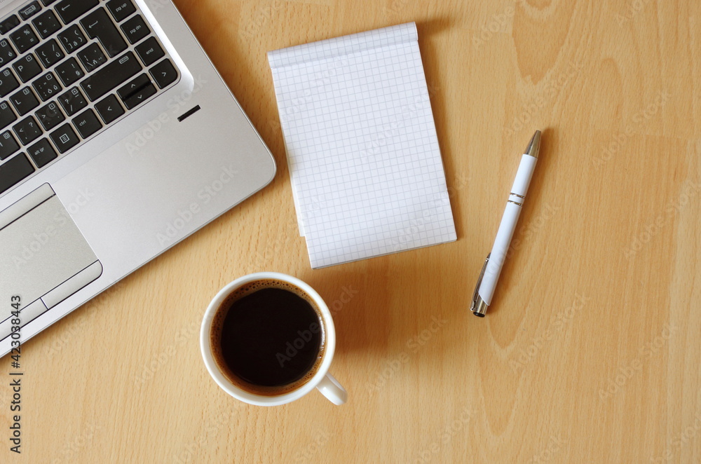 Laptop with coffee cup, notebook and pen on wooden background Top view. Concept for home office. Business concept. Work from home. Desk with laptop, blank notepad, coffee cup and pen on wooden table. Laptop with coffee cup, notebook and pen on wooden background Top view. Concept for home office. Business concept. Work from home. Desk with laptop, blank notepad, coffee cup and pen on wooden table.