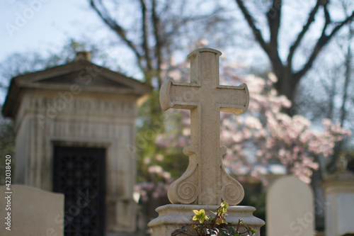 symbol of spirituality at blurred springtime cemetery with stone cross