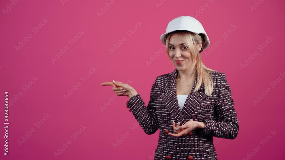 Beautiful blonde with an engineer's helmet on her head, recommends on the left side, at the end she shows her thumb young mature blonde in pink jacket. Beautiful blonde with an engineer's helmet on her head, recommends on the left side, at the end she shows her thumb young mature blonde in pink jacket.