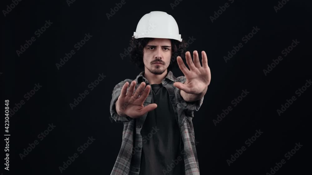 Determined hipster with curly hair, looks with stop hand, no, forbids something. Determined hipster with curly hair, looks with stop hand, no, forbids something.