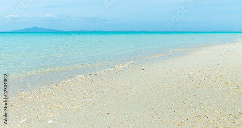 Soft blue ocean wave on clean sandy beach 