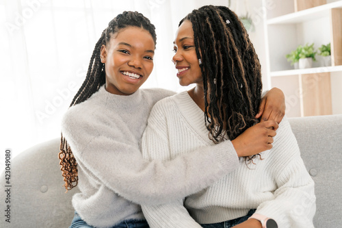 Mother and daughter sitting on sofa at home photo