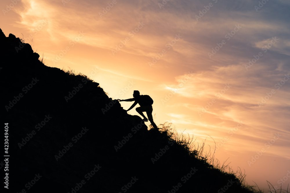 Male hiker climbing up a steep mountain cliff. People taking risk, motivation and outdoor adventure concept.	