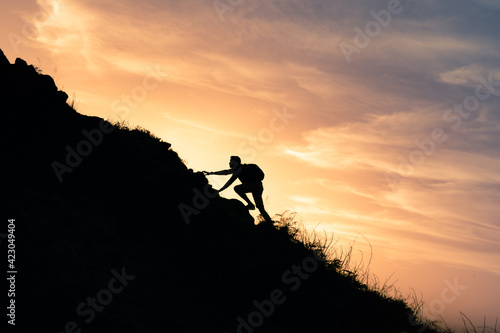 Male hiker climbing up a steep mountain cliff. People taking risk, motivation and outdoor adventure concept. 