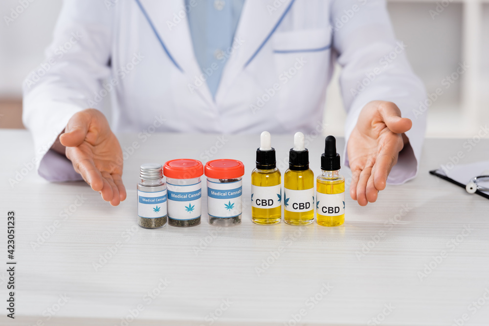 cropped view of african american doctor pointing with hands at bottles with medical cannabis and cbd cropped view of african american doctor pointing with hands at bottles with medical cannabis and cbd