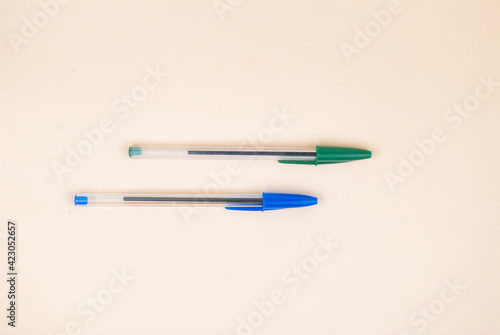 Two automatic ballpoint pens on a gentle pastel background. Two colored pens, blue and green.
