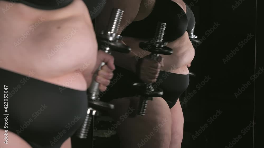 A bicep curl work out of the lady infront of the mirror only wearing the black undies. selective focus