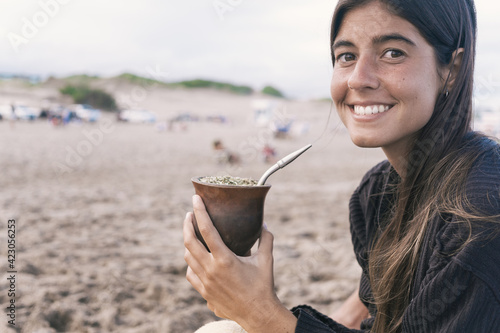 Beautiful young woman drinking traditional yerba mate tea