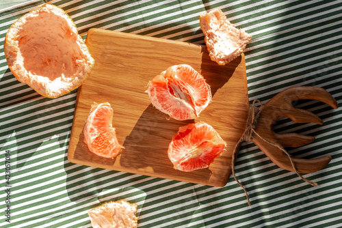Fresh peeled grapefruit illuminated by sunlight on a wooden board