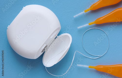 Interdental brush and floss for interdental spaces on blue background close up