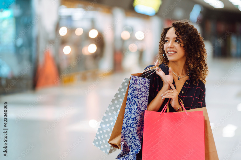 Young woman after shopping with shopping bags walks in the mall. Spring shoopping. Purchases, black friday, discounts, sale concept. Young woman after shopping with shopping bags walks in the mall. Spring shoopping. Purchases, black friday, discounts, sale concept.