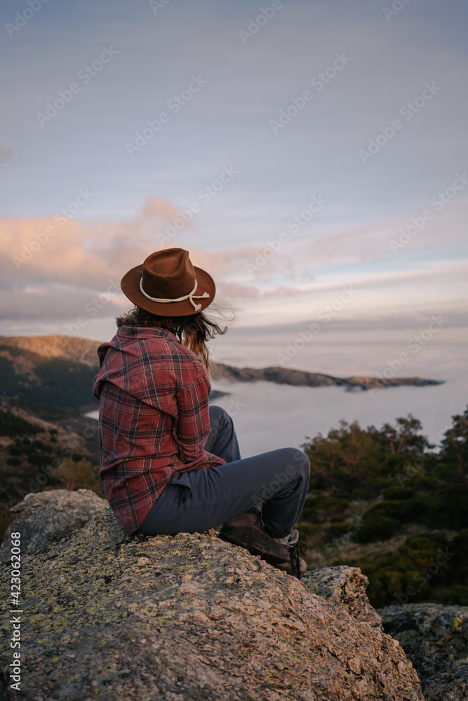 Back view of unrecognizable female tourist in hat admiring ocean with horizon from mountain under cloudy sky Back view of unrecognizable female tourist in hat admiring ocean with horizon from mountain under cloudy sky