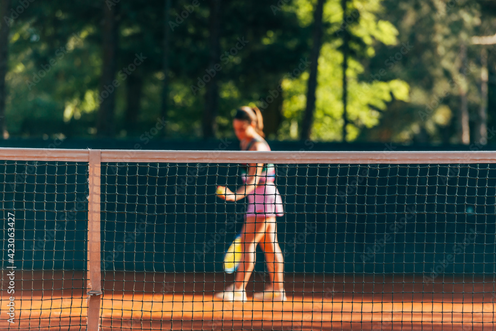 Pretty female tennis player observed through the net. Pretty female tennis player observed through the net.