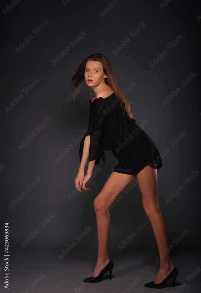 High fashion portrait of an elegant woman in a short black dress.