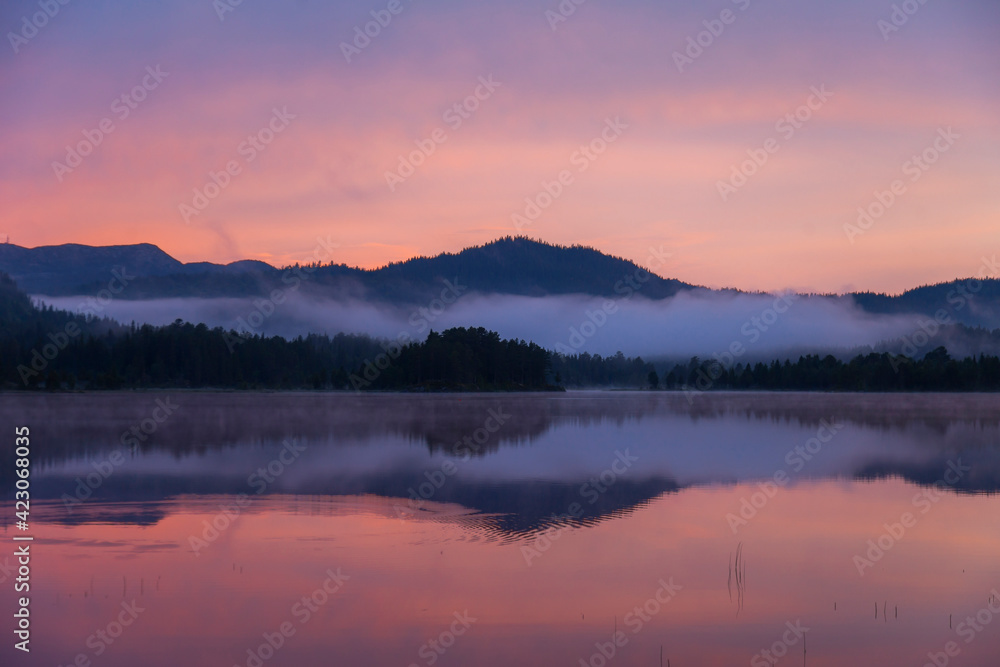 Scenic view of lake with smooth surface located in mountainous terrain under sunset sky in Norway Scenic view of lake with smooth surface located in mountainous terrain under sunset sky in Norway