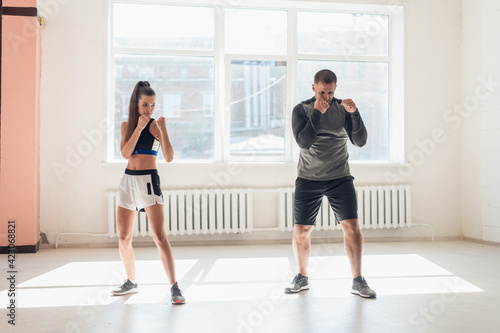 Woman training boxing with personal trainer. Instructor teaching female boxer fighting practice together