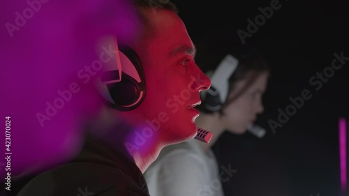 Portrait of a man playing a video game with a smile. In the foreground, a man is talking over a microphone. High quality 4k footage