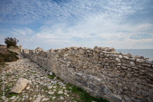 A stone wall in Cyprus in the ancient city of Amathus. An ancient building near Larnaca. Landscape with blue sky and sea photo