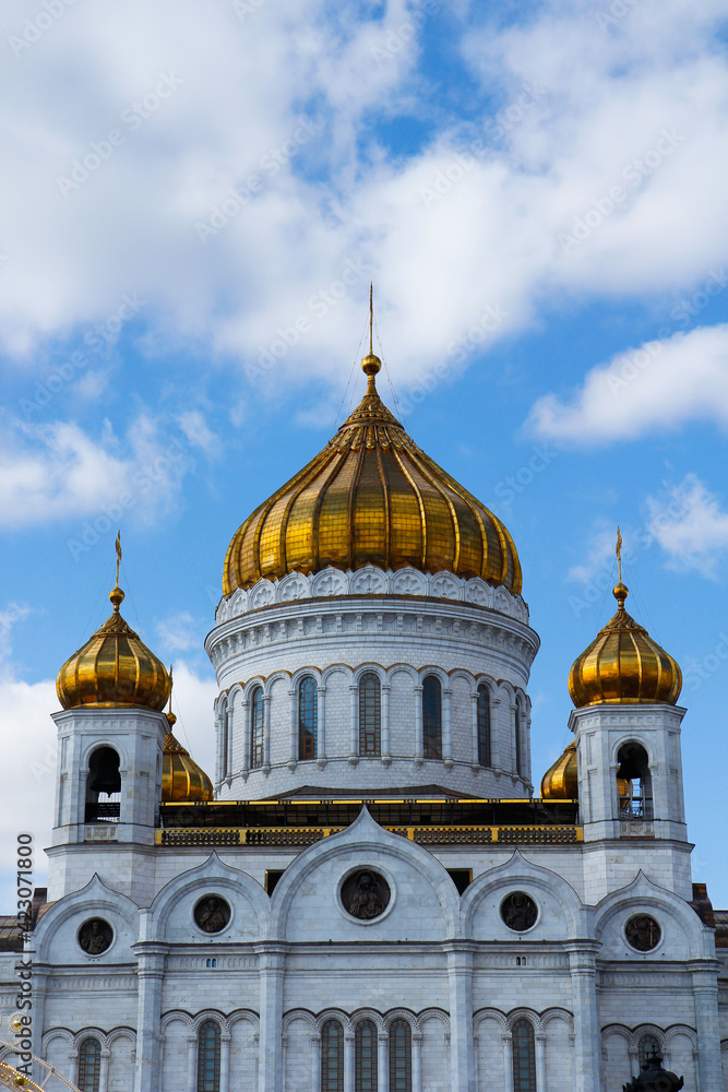 The domes of the Cathedral of Christ the Savior, shot up close, against a blue sky with clouds on a sunny day. Architecture and travel concept.