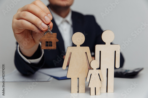 Broker holds a house keys for a young family. Mortgage concept