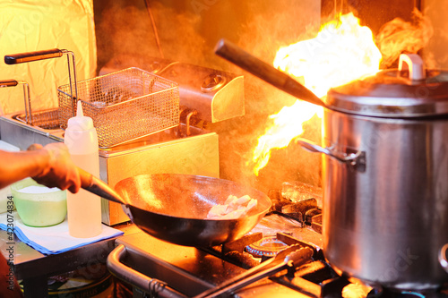 Stock photo of unrecognized chef using hot saucepan in the kitchen of japanese restaurant. photo