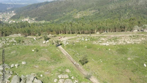 Mountain Bikers arduously climbing to Alto Minho mountain top Portugal - Aerial Wide Orbit tracking shot photo