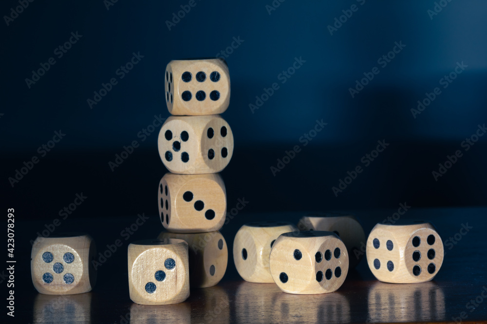 Wooden dice for board game stacked on wooden table and dark background. Wooden dice for board game stacked on wooden table and dark background.
