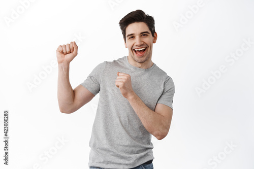 Joyful caucasian man dancing and having fun, smiling upbeat, standing upbeat against white background, celebrating and partying