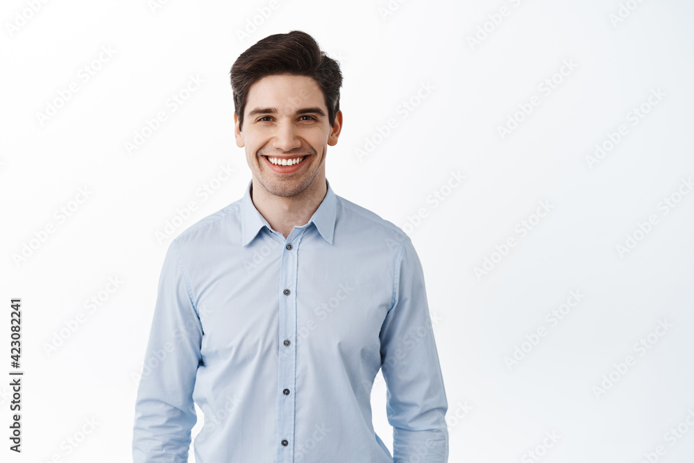 Portrait of successful businessman, happy office worker ceo smiling pleased, standing against white background in blue collar shirt Portrait of successful businessman, happy office worker ceo smiling pleased, standing against white background in blue collar shirt