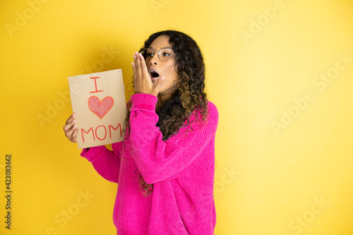 Beautiful woman celebrating mothers day holding poster love mom message bored yawning tired covering mouth with hand. Restless and sleepiness.