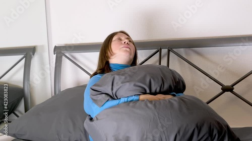 sad, serious adult middle-aged plump woman sitting at home in bed, suffering from abdominal pain, worries about problems, loneliness, hugging a pillow, concept female cycle, menopause