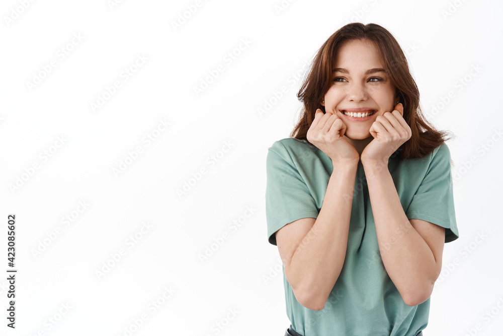 Image of young grateful and happy girl jumping from happiness, looking with admiration and joy aside at logo banner, standing against white background Image of young grateful and happy girl jumping from happiness, looking with admiration and joy aside at logo banner, standing against white background