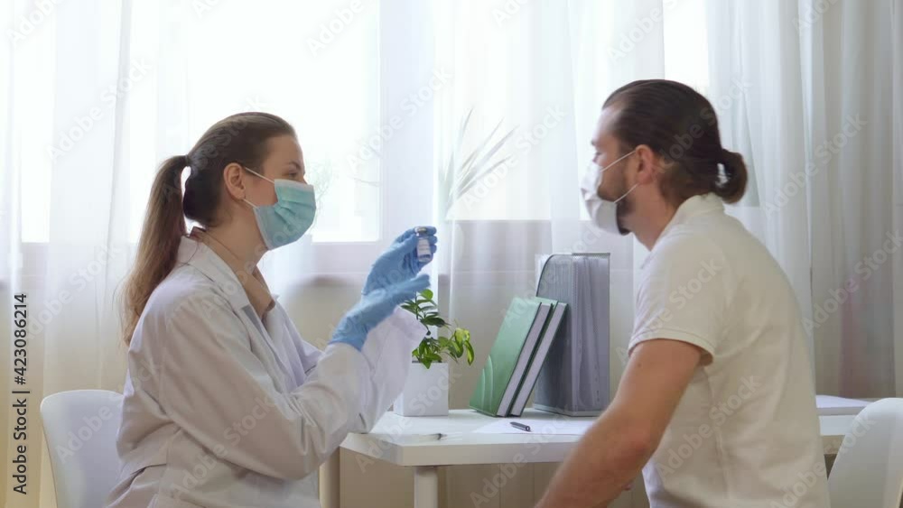 A female doctor tells a male patient about the new coronavirus vaccine and show casing covid 19. At a medical clinic, laboratory view. A female doctor tells a male patient about the new coronavirus vaccine and show casing covid 19. At a medical clinic, laboratory view.
