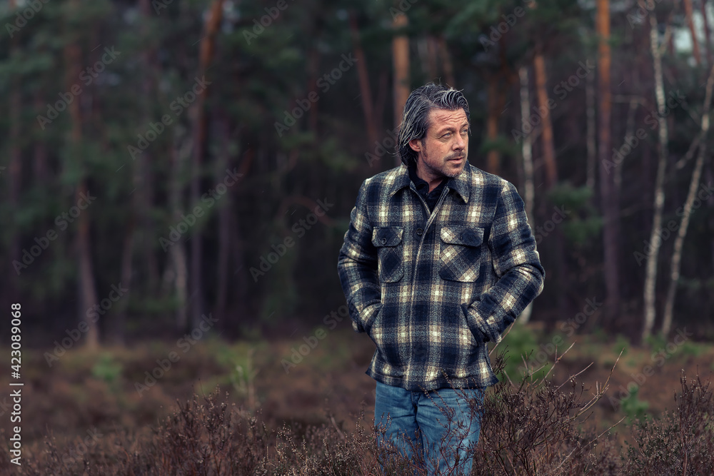 Man with stubble beard in a checkered coat in a rainy heathland. Man with stubble beard in a checkered coat in a rainy heathland.