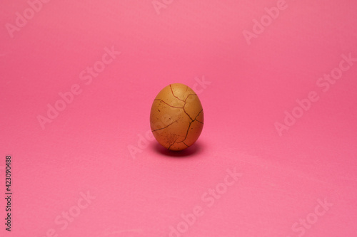 Chicken organic brown egg  with cracked like paint. Pink background. Minimal Easter background
