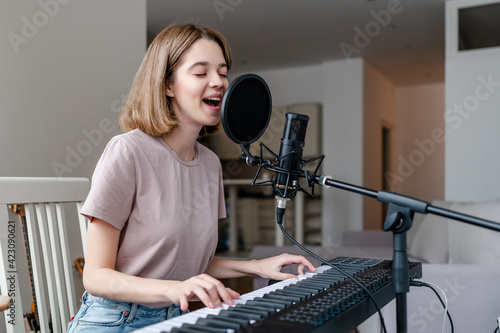 young woman playing piano and singing a song at home