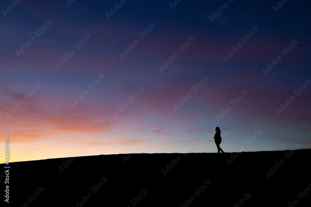 silhouette of a person standing on the top of a mountain