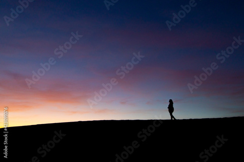 silhouette of a person standing on the top of a mountain