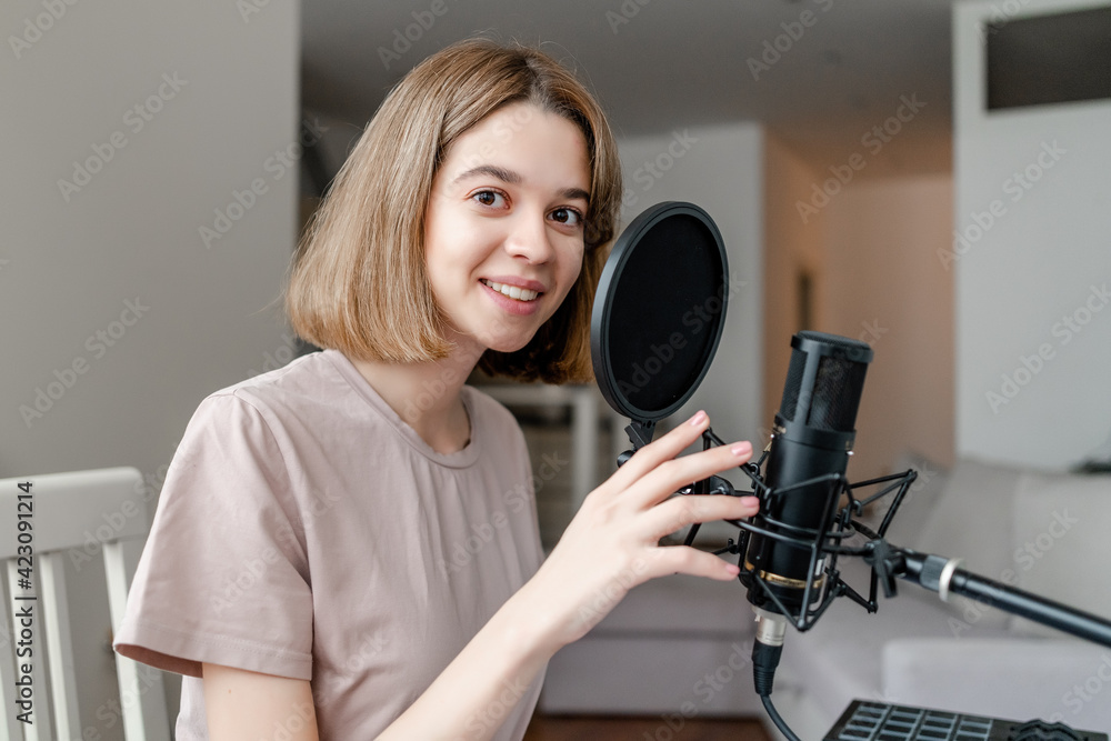 young woman smiling and singing in microphone in homestudio young woman smiling and singing in microphone in homestudio
