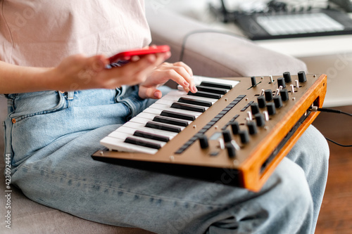 Canvas Print woman hands playing minilogue synthesizer using mobile app at home closeup