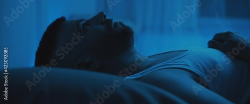 Close up of a soldier lying on bed, staring at the ceiling, dealing with post trauma.