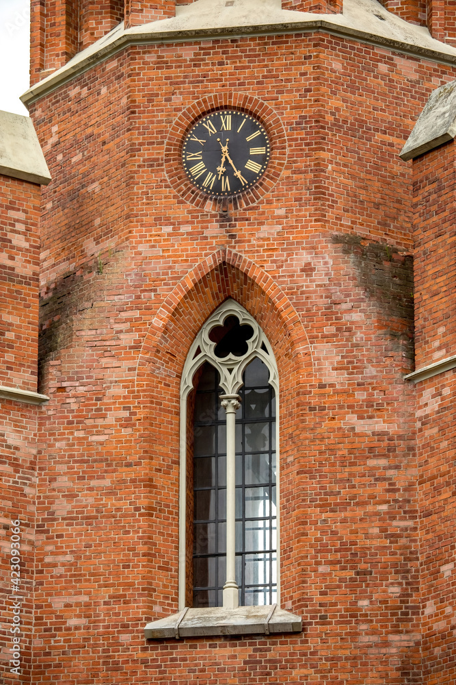 Fototapeta premium Ornate window and clock on the wall of Church of St Matthew the Apostle, Rokiskis, Lithuania